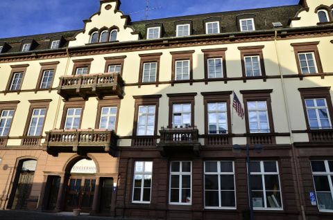 Ein historisches Gebäude mit einem hellen, gelben Anstrich und mehreren Fenstern. Die Balkonverzierungen und das gepflegte Erscheinungsbild verleihen ihm einen charmanten Charakter.