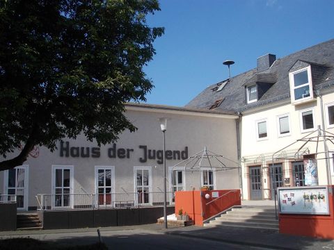Ein modernes Gebäude mit der Beschriftung "Haus der Jugend". Es hat helles Licht und einen klaren Himmel im Hintergrund.