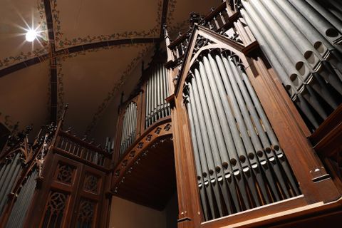 A magnificent wooden church organ with many pipes. The view from below reveals the intricate construction and details of the instrument.