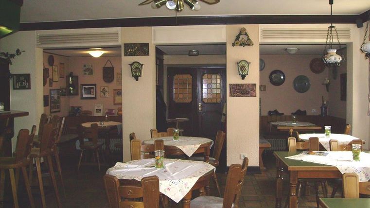 Een gezellig restaurant met houten stoelen en tafels. De wanden zijn versierd met foto's en decoraties.