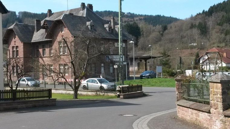 Historisches Bahnhofsgebäude in Zendscheid mit umliegender Landschaft.