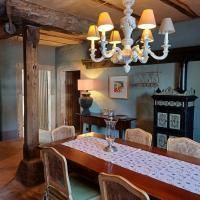 Une salle à manger confortable avec une grande table en bois et des chaises élégantes. Un lampadaire décoratif et une commode raffinée ajoutent du charme à la pièce.