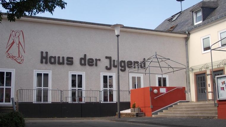 A building with the sign "Haus der Jugend." It has large windows and an accessible staircase.