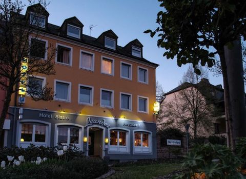 Ein gemütliches Hotel mit einladendem Bistro und Restaurant. Die Fassade ist orange gestrichen und bei Dämmerung beleuchtet.