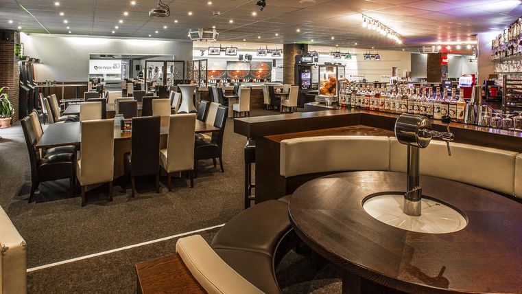 Ein modernes Restaurant mit eleganten Tischen und Stühlen. Die Atmosphäre ist einladend, mit Einrichtung und Beleuchtung, die ein gemütliches Ambiente schaffen.