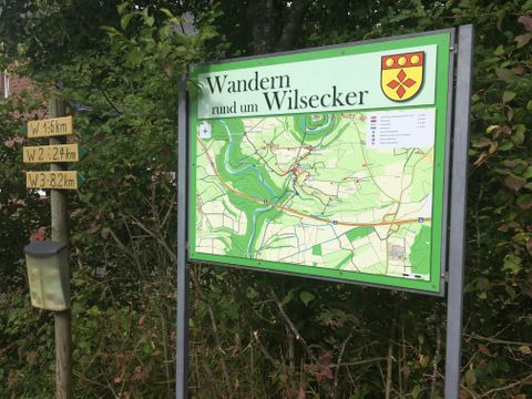 Infotafel mit Wanderkarte in Wilsecker, umgeben von Bäumen.