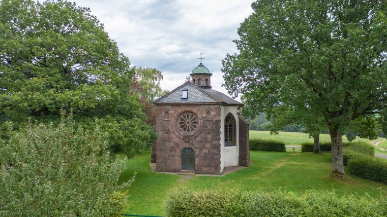 Frohnertkapelle in Oberkail, umgeben von Bäumen und Wiesen.