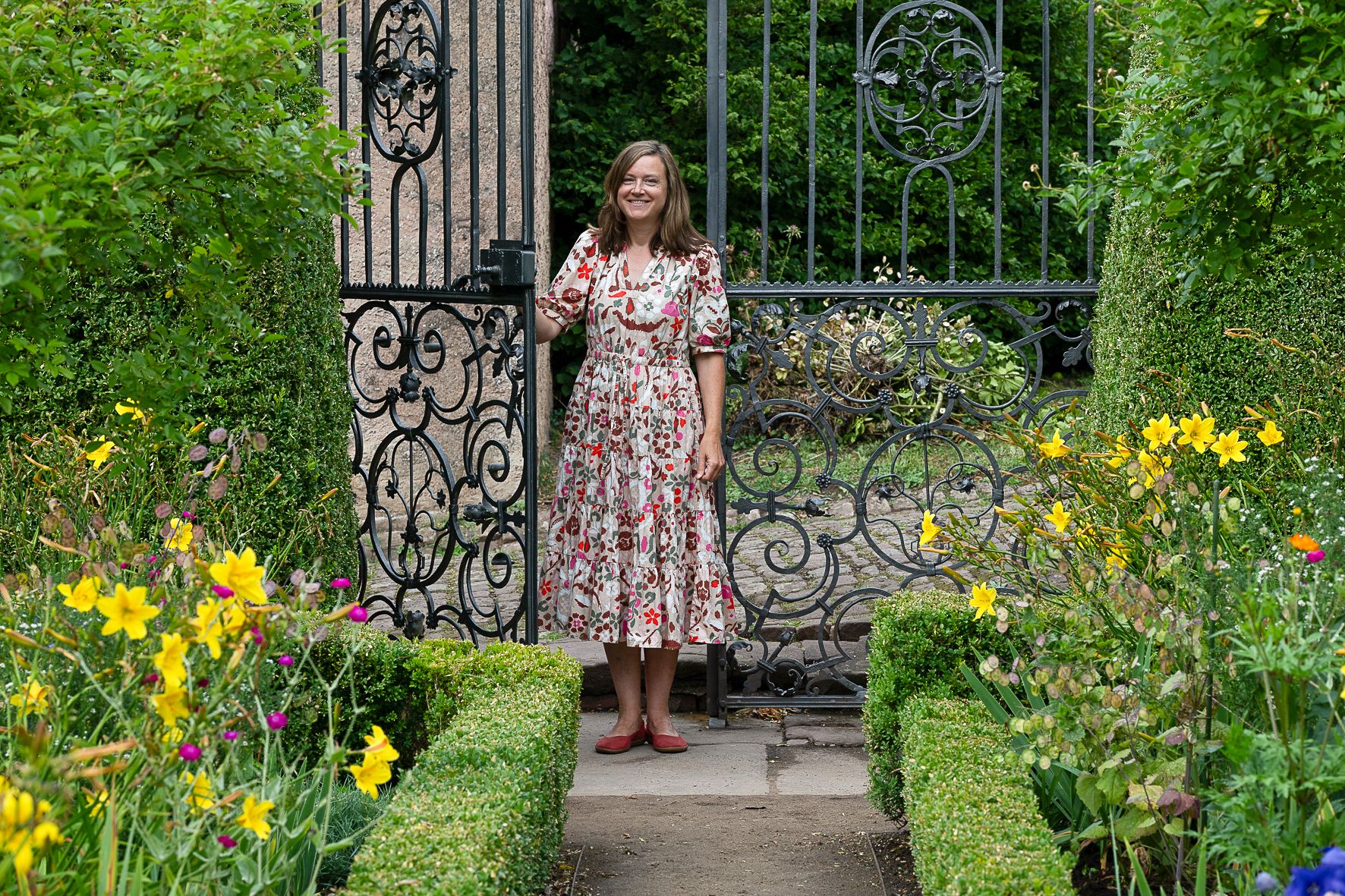 Bianca Höftmann steht im Eisernern Garten von Schloss Malberg. Blumen blühen.
