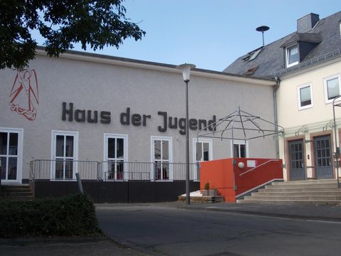 Ein modernes Gebäude mit der Beschriftung "Haus der Jugend". Der Eingangsbereich ist freundlich gestaltet und hat eine eckige Treppe.