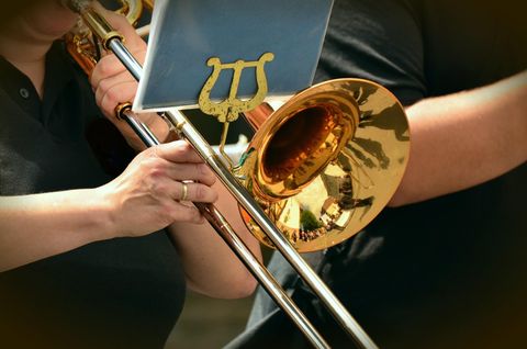 Een close-up van trompetten en muzikanten. De glanzende instrumenten stralen in het licht.