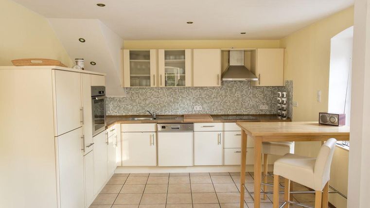 Eine moderne Küche mit weißen Möbeln und einer hellen, freundlichen Atmosphäre. Die Küche verfügt über eine Kochinsel und eine funktionale Anordnung.