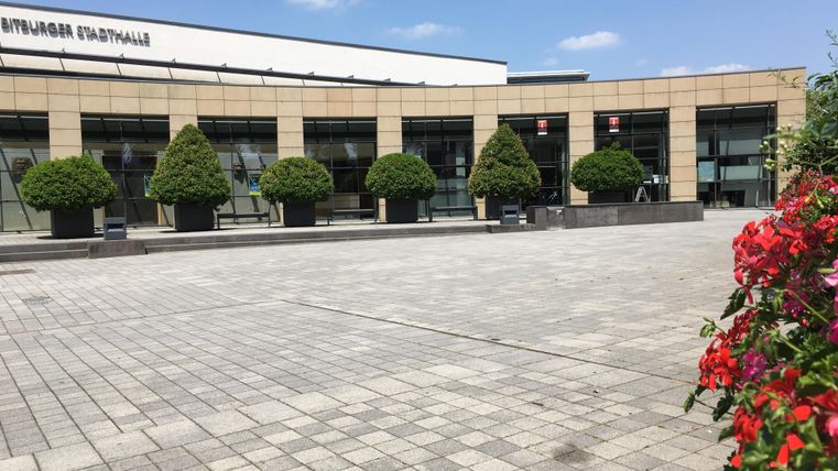 A modern building with large windows and low-maintenance plants in the foreground. The area is paved and offers an inviting atmosphere.