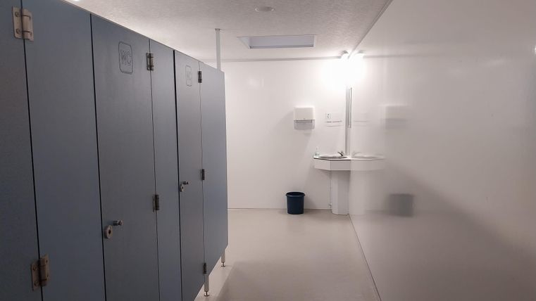 Une salle de vestiaire lumineuse avec des casiers bleus et un lavabo. La pièce est propre et conçue de manière minimaliste.