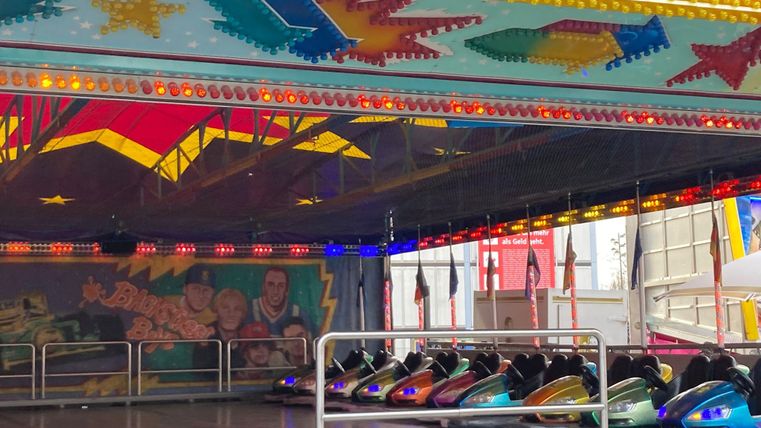 Een attractie met auto's in felle kleuren staat klaar. Het interieur is versierd met heldere lichten en grafieken.