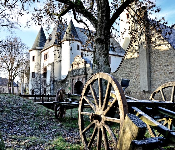 Kasteel Rittersdorf in de winter, omringd door kale bomen. Op de voorgrond zorgen oude houten wagenwielen voor een historische sfeer., © TI Bitburger Land