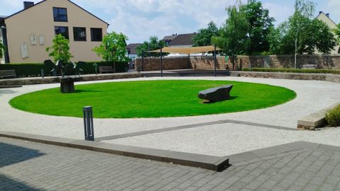 Un parc rond avec une pelouse verte et des sièges confortables. Entouré d'arbres et d'une conception moderne.