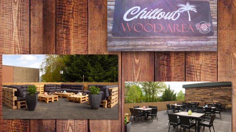 Ein rustikaler Außenbereich mit gemütlichen Sitzgelegenheiten aus Holzpaletten. Der Bereich ist ideal zum Entspannen und ist von grünen Pflanzen umgeben.