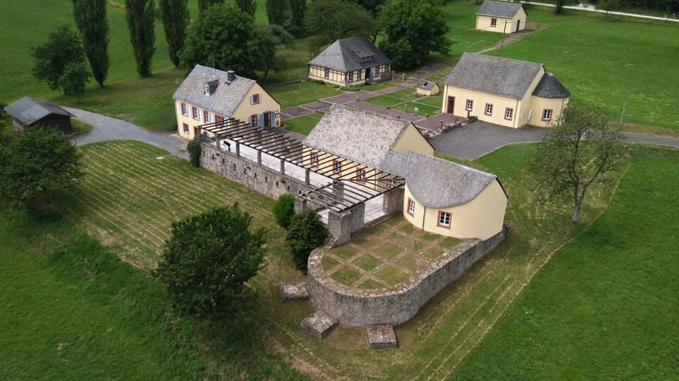 Ein malerischer Bauernhof mit mehreren Gebäuden und einem großen, grünen Gelände. Umgeben von Bäumen und Wiesen vermittelt er einen ruhigen ländlichen Eindruck.