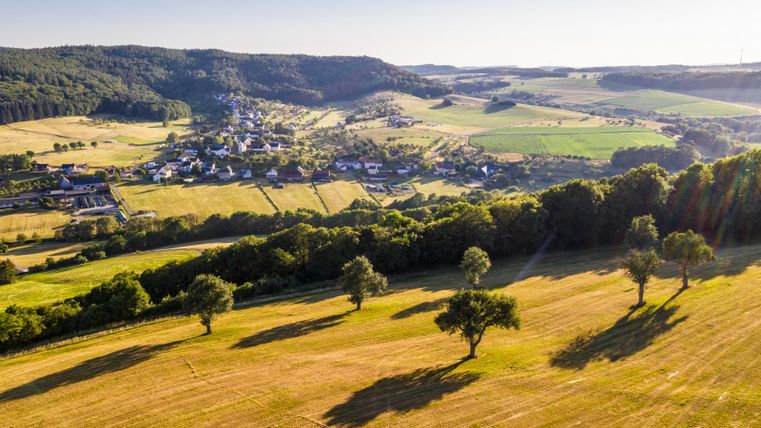Landschaft im Enztal mit Feldern, Bäumen und einem Dorf im Hintergrund.
