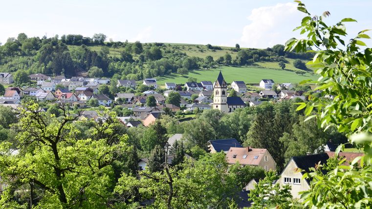 Panoramablick auf das Dorf Oberweis mit Kirche und grüner Landschaft im Hintergrund.