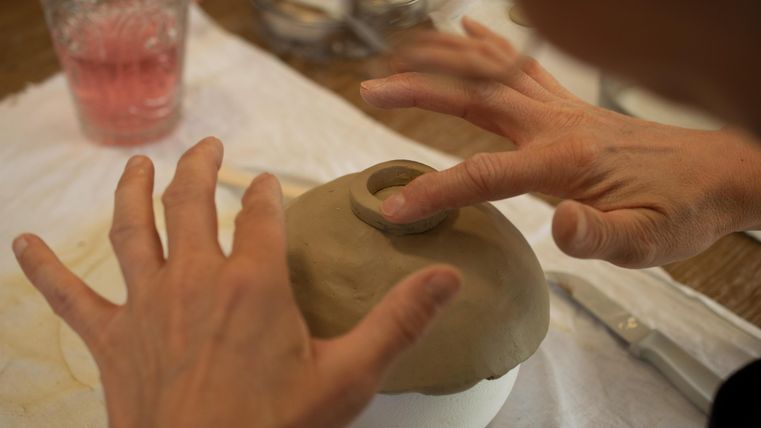 Deux petites maisons en céramique blanches avec des fenêtres en forme de cœur. Elles se trouvent sur un fond à motifs colorés.