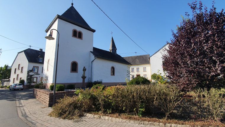 Kapelle St. Luzia in einem Dorf mit blauem Himmel.