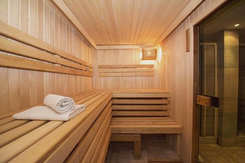 Een heldere sauna met houten banken en zachte verlichting. Een vers handdoek ligt klaar.