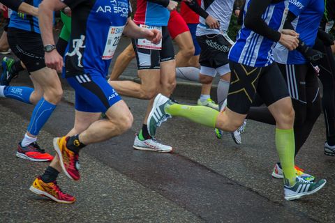 Eine Gruppe von Läufern beim Wettlauf. Die Teilnehmer tragen sportliche Kleidung und verschiedene Laufschuhe.