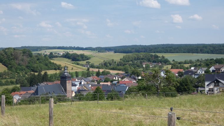 Panoramablick auf Gransdorf mit Kirche im Vordergrund und grüner Landschaft im Hintergrund.