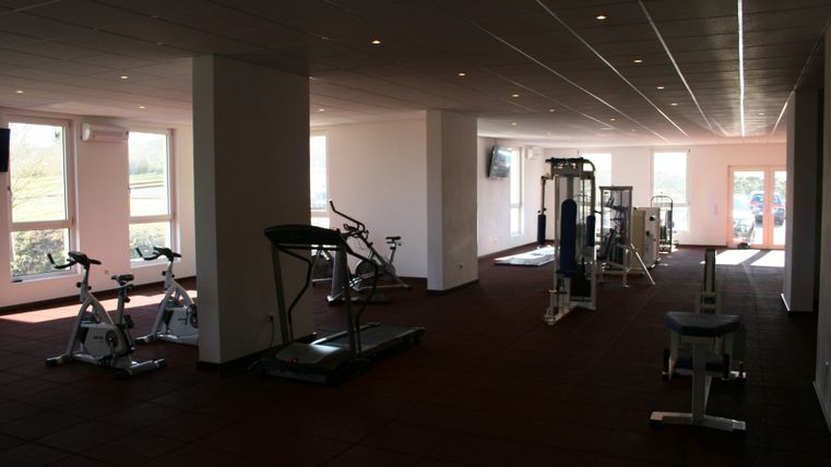 Ein modernes Fitnessstudio mit verschiedenen Trainingsgeräten. Viel Platz und große Fenster sorgen für eine helle, einladende Atmosphäre.
