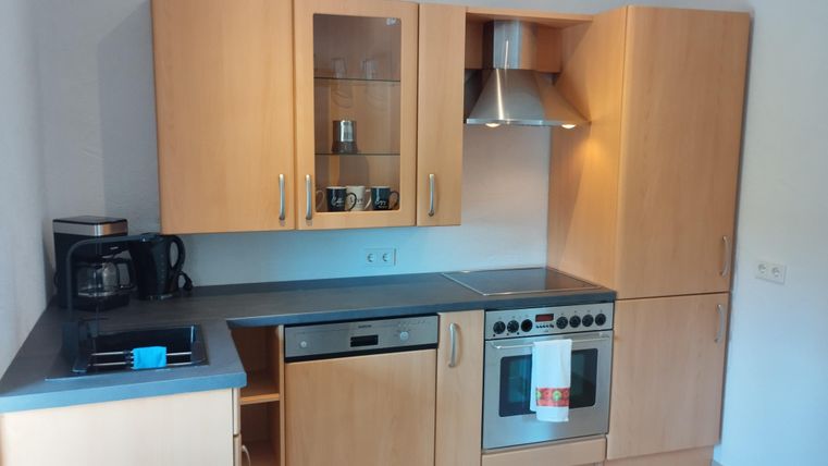 Eine moderne Küche mit hellen Holzschränken und Edelstahlgeräten. Der Raum ist gut beleuchtet und bietet eine praktische Anordnung der Küchenutensilien.