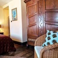 Une chambre confortable avec une armoire en bois et une chaise en osier. Elle est chaude et accueillante avec un charme rustique.