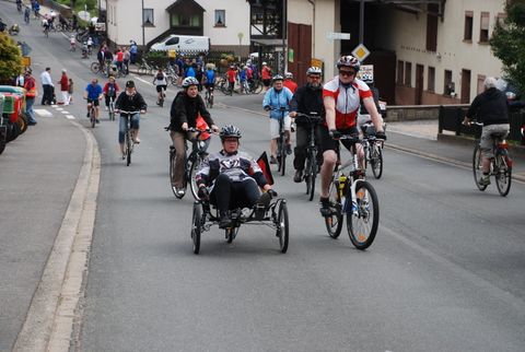 viele Radfahrer auf einer Straße in einer Ortschaft.