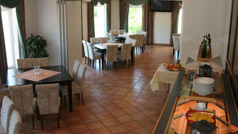 Ein eleganter Speisesaal mit Tischen und Stühlen. An einer Seite befindet sich ein Buffet mit verschiedenen Gerichten.