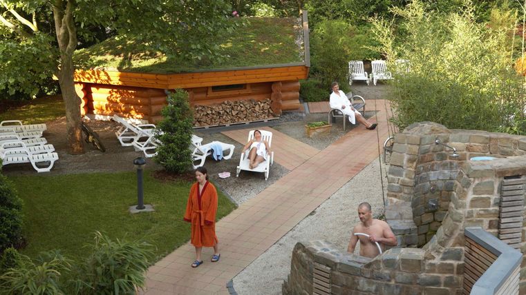 Een ontspannend wellnessgebied met natuurstenen muren en een tuin. Mensen genieten van de rust en ontspanning in de buitenlucht.