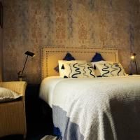 Une chambre confortable avec un grand lit et des coussins décoratifs. Les murs ont une texture élégante, et l'éclairage crée une atmosphère chaleureuse.