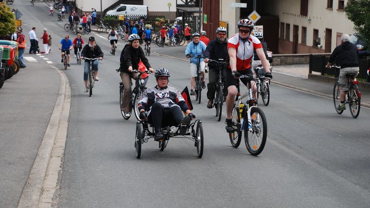 viele Radfahrer auf einer Straße in einer Ortschaft.