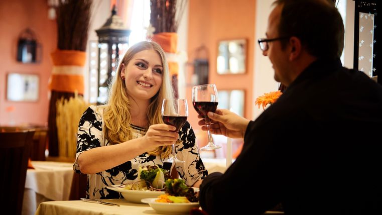 Ein romantisches Abendessen in einem Restaurant. Ein Paar prostet sich mit Weingläsern zu und genießt die gemeinsame Zeit.