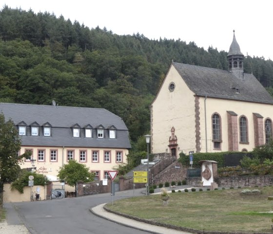 Église de l'Assomption à Auw, sur le chemin de pèlerinage Speicher, entourée de bâtiments et d'une forêt en arrière-plan., © Eifelverein Ortsgruppe Speicher
