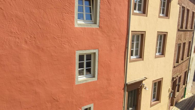 Bunte Hausfassaden in einer ruhigen Straße. Die Gebäude sind hell und einladend.