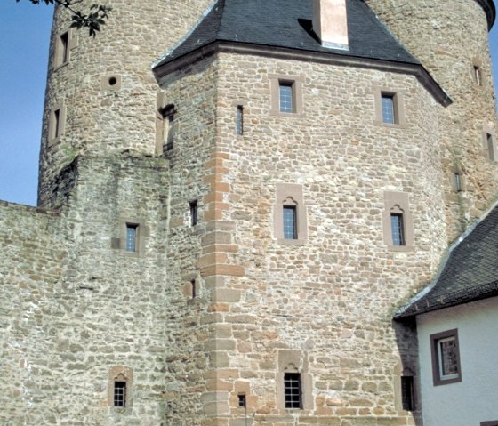Le château de Bertrada à Mürlenbach présente deux tours rondes et un arc de porte en pierre sous un ciel bleu et clair., © TI Bitburger Land