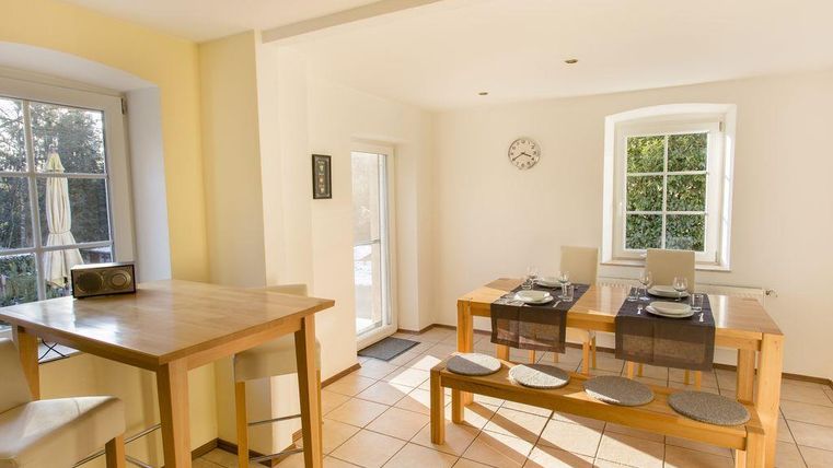 Eine helle und moderne Küche mit einem Essbereich. Der Tisch ist gedeckt und es gibt eine große Fenstertür, die nach draußen führt.