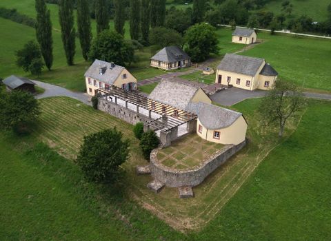 Eine malerische Landschaft mit mehreren reizvollen Gebäuden. Umgeben von grünem Gras und Bäumen, bietet die Szenerie eine ruhige Atmosphäre.