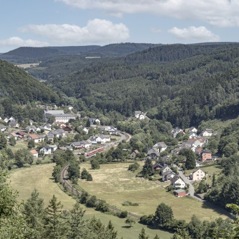 Panoramic view of a village in a green valley, surrounded by wooded hills and meadows. A train runs through the village., © Rudolf Höser