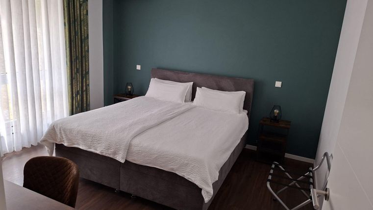 Une chambre moderne avec deux lits jumeaux et un design minimaliste.
Les murs sont peints dans une teinte verte apaisante et de grandes fenêtres laissent entrer beaucoup de lumière naturelle.