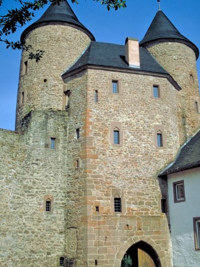 Bertradaburg in Mürlenbach mit zwei runden Türmen und einem Torbogen.