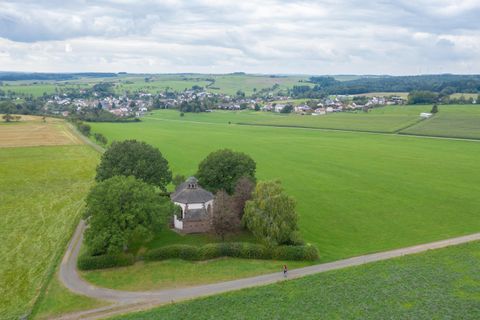 Landschaft mit Kapelle und Dorf im Hintergrund.