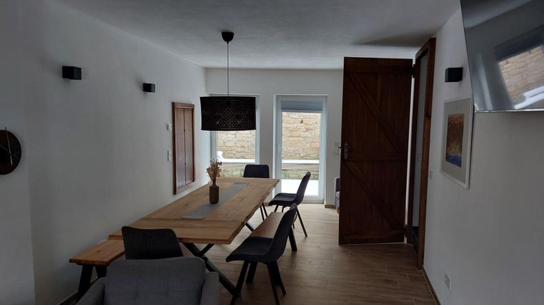 Een lichte, moderne eetkamer met een grote houten tafel en zwarte stoelen. Grote ramen laten veel daglicht binnen.