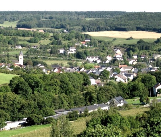 Vue panoramique sur le village d'Oberweis avec son église, entouré de champs et de forêts verdoyants dans le Bitburger Land., © P. J. Evertz