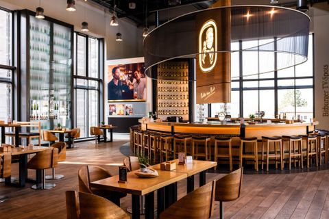 Een modern restaurant met een gezellige bar en veel natuurlijk licht. Het interieur is van hout en straalt een gezellige sfeer uit.